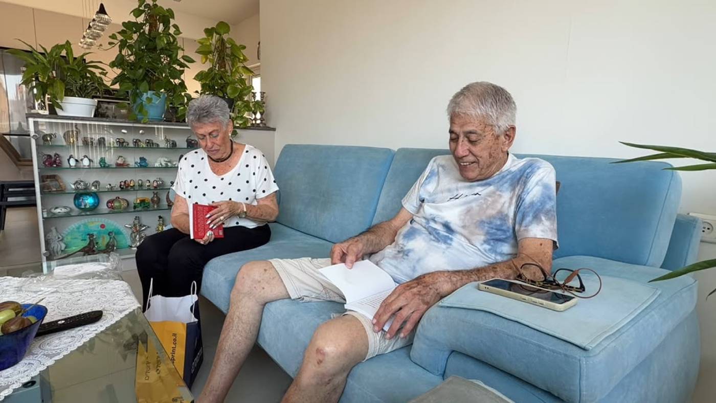 Adina and Nehemia reading their own printed books on the sofa at home.